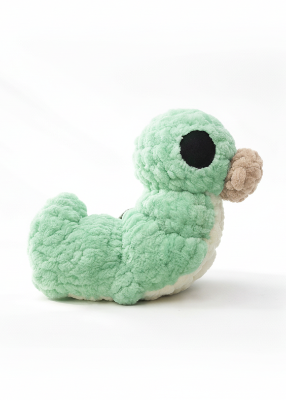 Plush toy grub from hollow knight with a green body andbig eyes and bulging beige mouth on a white background