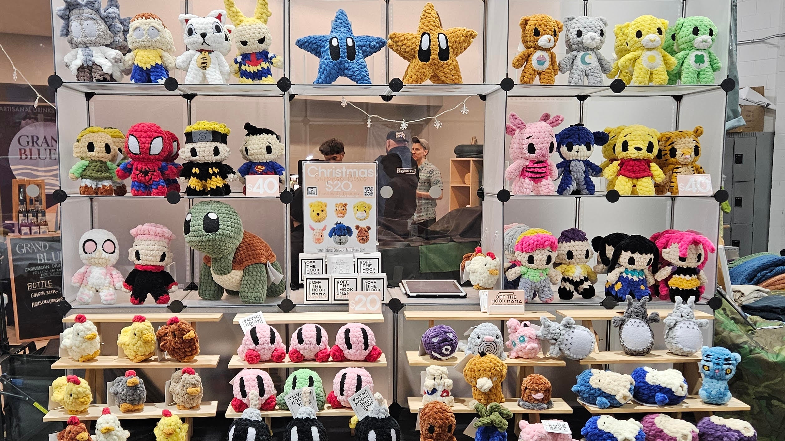 Display of various plush toys on a table with 'Off the Hook Mama' branding.
